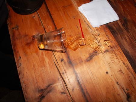 A broken glass on a wooden table in a restaurant. Close-up.の写真素材