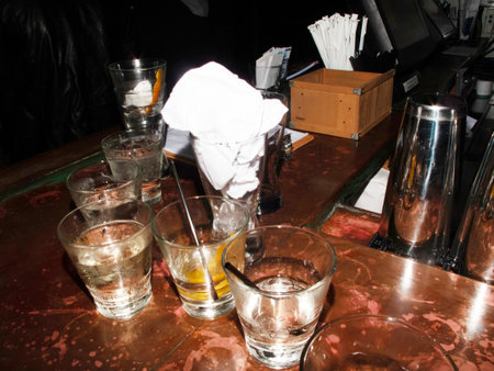Barman pouring alcohol in a glass with ice cubes on a bar counterの写真素材