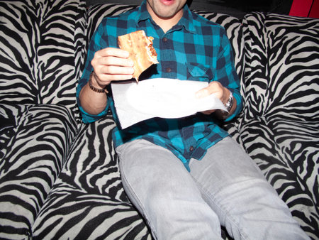 A man eating pizza on a sofa in the living room at homeの写真素材