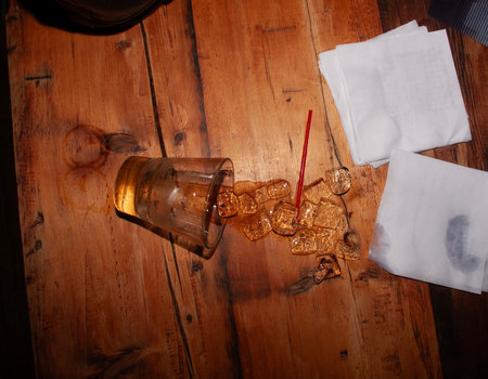 A glass of whiskey with ice cubes on a wooden table, top viewの写真素材