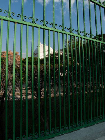 Detail of a green metal fence with a church in the backgroundの写真素材