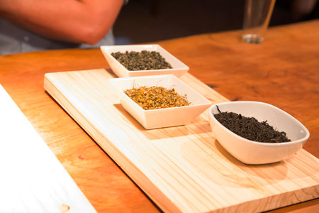Dry tea leaves in white ceramic bowls on wooden table in restaurantの写真素材