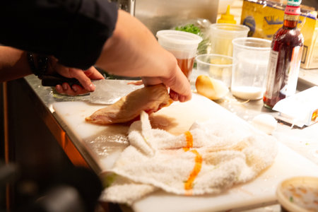 Chef at work in a restaurant kitchen preparing fresh chicken filletsの写真素材