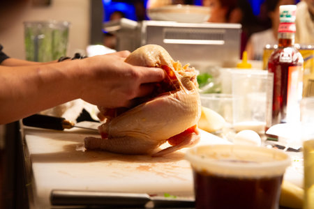 Hands of a chef preparing a chicken on a table in a restaurantの写真素材