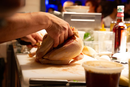 Close-up of the hands of a professional chef who is preparing a chicken in a restaurantの写真素材