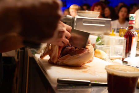 Chef cutting raw chicken with knife on a table in a restaurantの写真素材