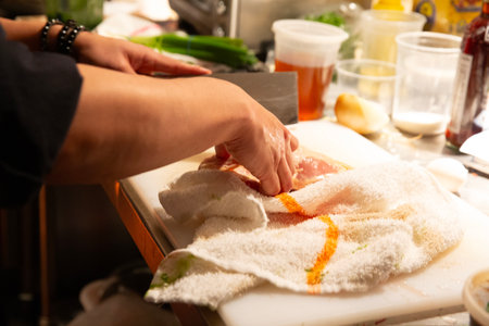 Closeup of a woman's hands cutting meat in the kitchen.の写真素材