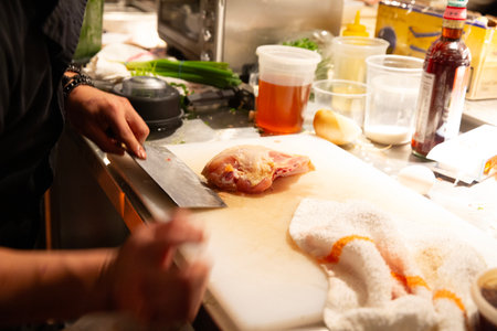 chef cutting raw chicken fillet for cooking in a restaurant kitchenの写真素材