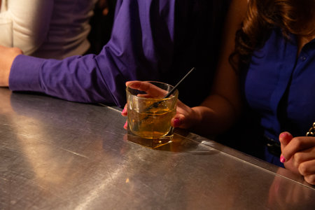 Close up of hands holding a cocktail at a bar.の写真素材