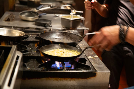 cooking omelet in a pan on the fire in the restaurantの写真素材