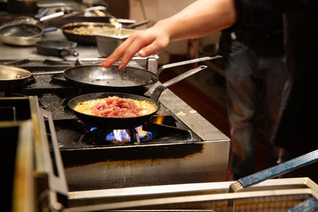 chef cooking omelette in a pan on the fire stoveの写真素材