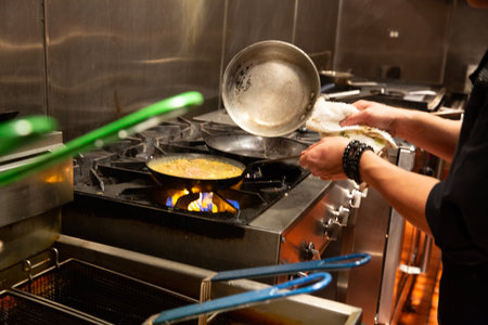 Chef cooking omelette on a gas stove in a restaurant kitchenの写真素材