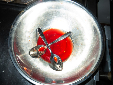 Two spoons in a bowl of red sauceの写真素材