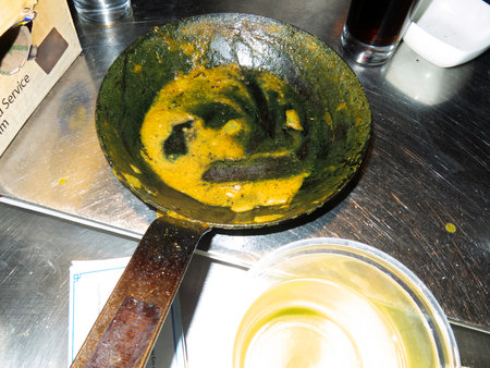 Frying pan with egg yolk on the stove in a restaurantの写真素材
