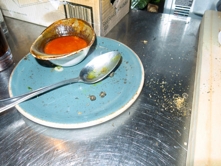 Stainless steel plate with spoon and bowl of tomato soup.の写真素材