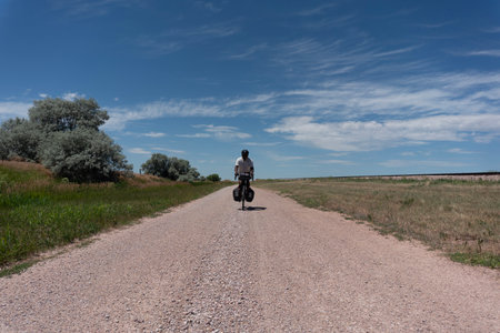 Young man riding a bike on a dirt road in the countryside.の写真素材