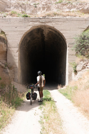 A man with a bicycle in the middle of a tunnel in the mountainsの写真素材