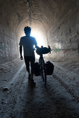 A silhouette of a man with a bicycle in an old tunnel.の写真素材