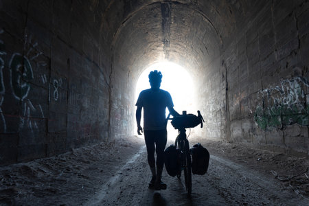 Silhouette of a man with a bicycle in an old tunnelの写真素材