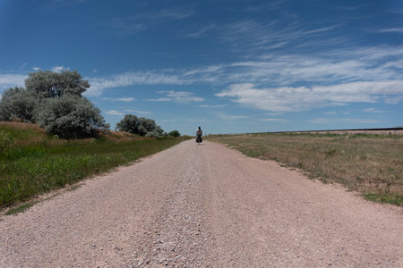 A man riding a bike on a dirt road in the countryside.の写真素材
