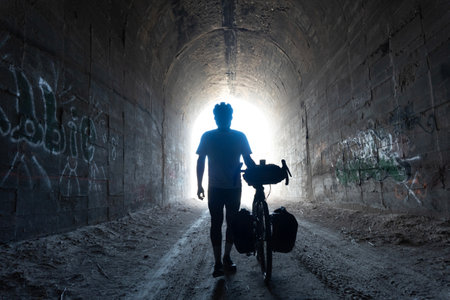 Silhouette of a man with a bicycle in an abandoned tunnelの写真素材