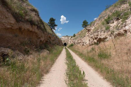 Dirt road in the mountains against the blue sky with clouds.の写真素材