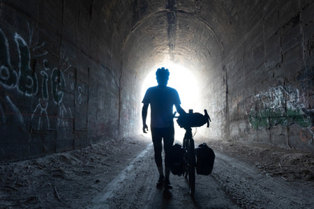 Silhouette of a man with a bicycle in an old tunnelの写真素材