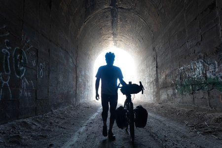Silhouette of a man with a bicycle in an old tunnelの写真素材