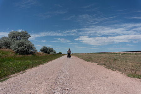 A person riding a bicycle on a dirt road in the countryside.の写真素材