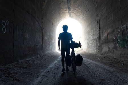 Silhouette of a man with a bicycle in an abandoned tunnelの写真素材
