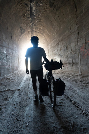 Silhouette of a man with a bicycle in a tunnel.の写真素材