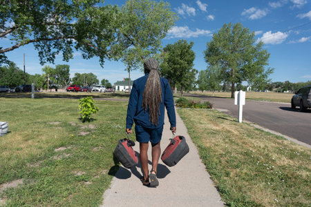 Rear view of an African American woman walking along a road with her wheelsの写真素材
