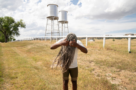 A black man with dreadlocks in front of a water tower.の写真素材