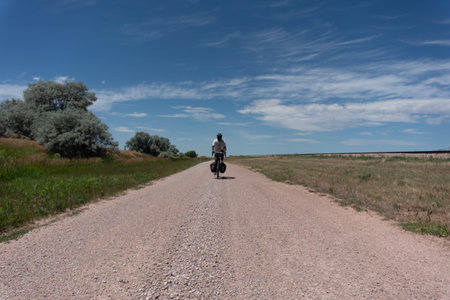 man riding a bike on a dirt road in the steppe.の写真素材