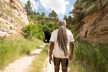 Rear view of a man with dreadlocks walking through a canyonの写真素材