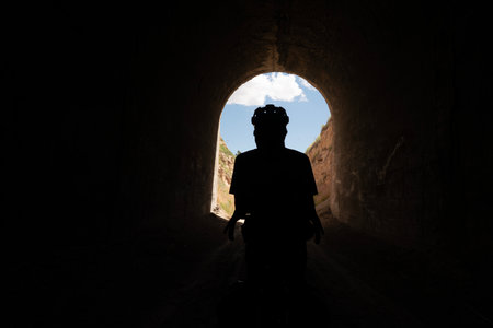 silhouette of a man walking in a tunnel with blue skyの写真素材