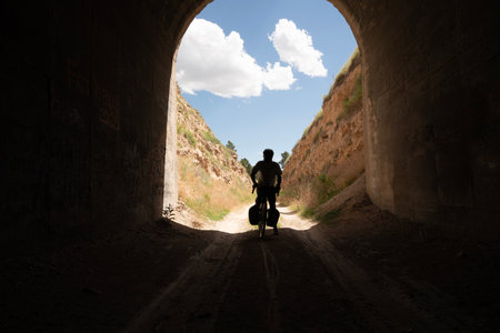 A man with a dog walks through an old tunnel in the mountainsの写真素材