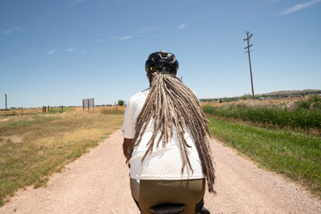 Rear view of a man with dreadlocks riding a scooterの写真素材