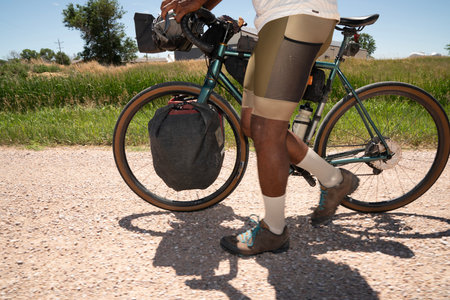 Low section of man with bicycle on country road during summerの写真素材