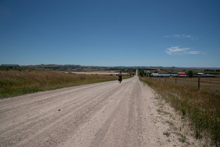 A country road in the middle of a field with a blue skyの写真素材