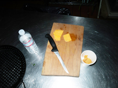 Chef cutting cheese on a cutting board with knife and bottle of waterの写真素材