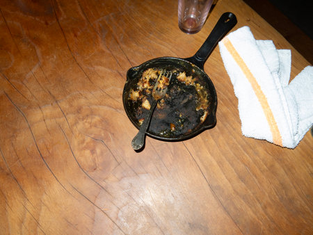 Dirty pan with fork on a wooden table, top viewの写真素材