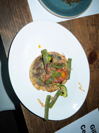 Spanish omelette with vegetables on a white plate in a restaurantの写真素材