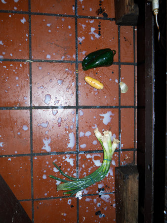 Green bell pepper, yellow potato, and green onions on the floorの写真素材