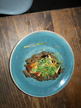 Rice with meat and vegetables on a blue plate on a wooden tableの写真素材