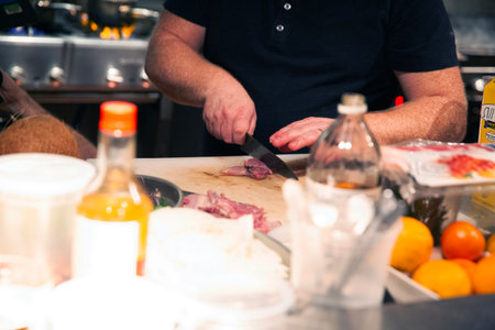 Chef cutting meat on a cutting board in a restaurant kitchen.の写真素材