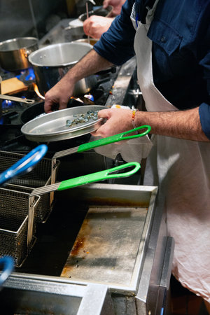 Chef preparing food in a restaurant kitchen, close-up.の写真素材