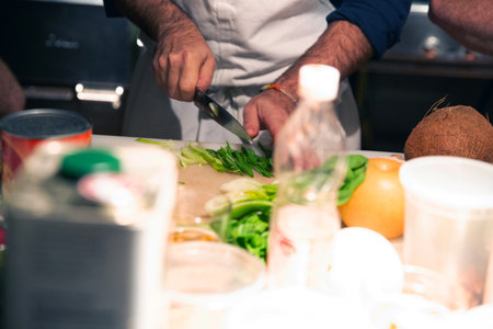 Close-up of a chef cutting vegetables on a chopping board in a commercial kitchenの写真素材