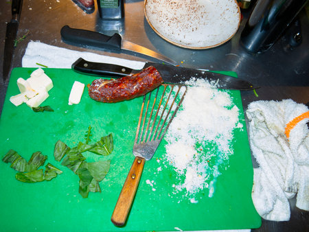 Sausage and cheese on a green cutting board with knife and forkの写真素材