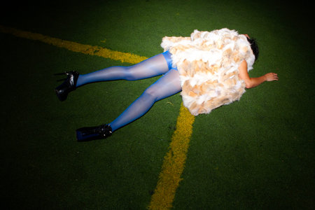 Sexy young woman in blue dress and fur coat lying on the grassの写真素材